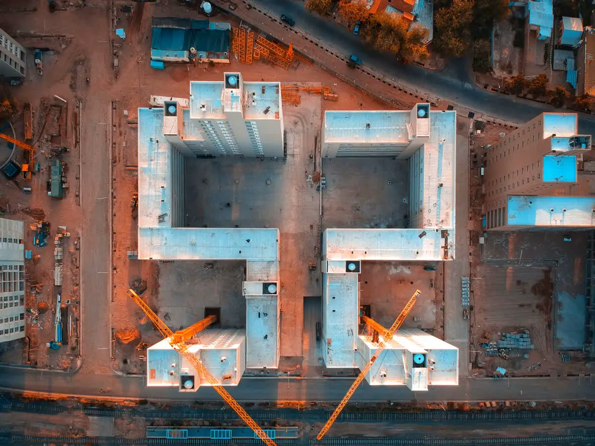 Top-down drone view of a building under construction with tower cranes