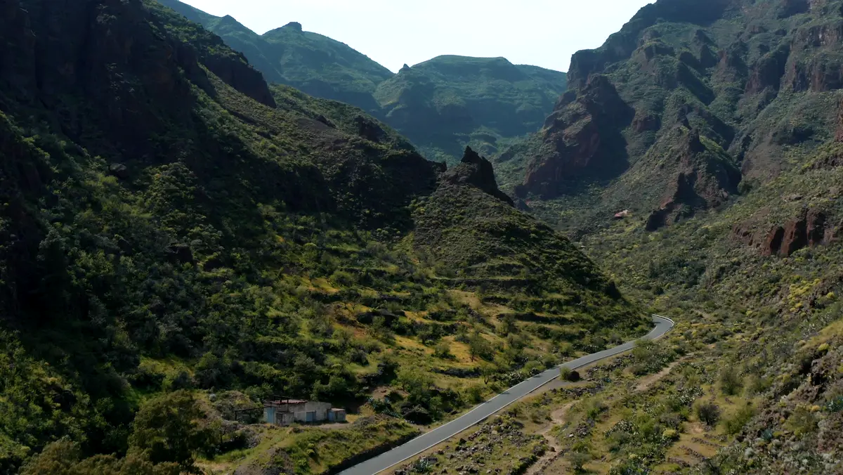 Cinematic drone shot of a road winding through a mountain canyon